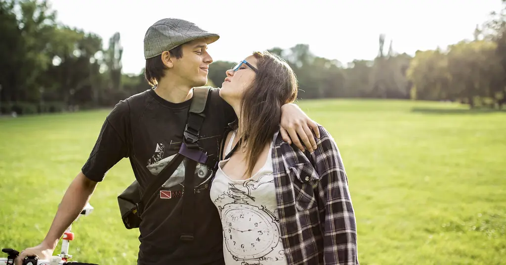 Site de rencontre : un jeune couple avec un vélo se sourit dans un parc