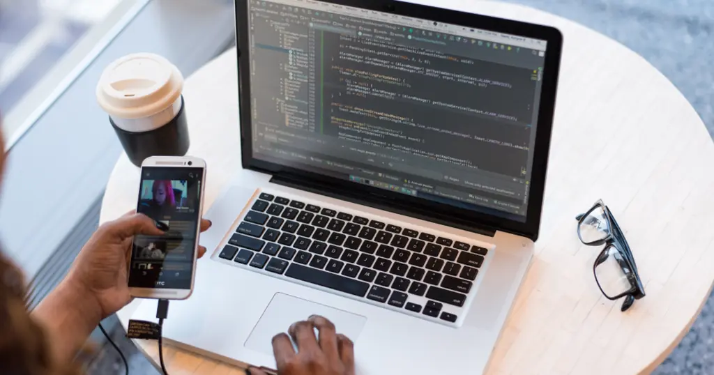 Créer son profil de rencontre : un smartphone et un ordinateur portable sur une table ronde