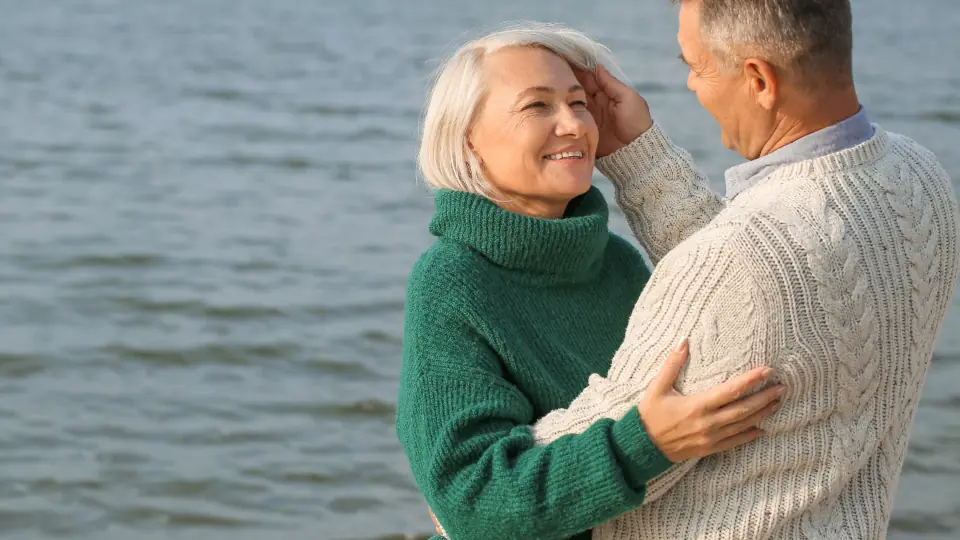 Un couple de plus de 50 ans s’enlace au bord de l’eau, rencontré grâce à un site de rencontre