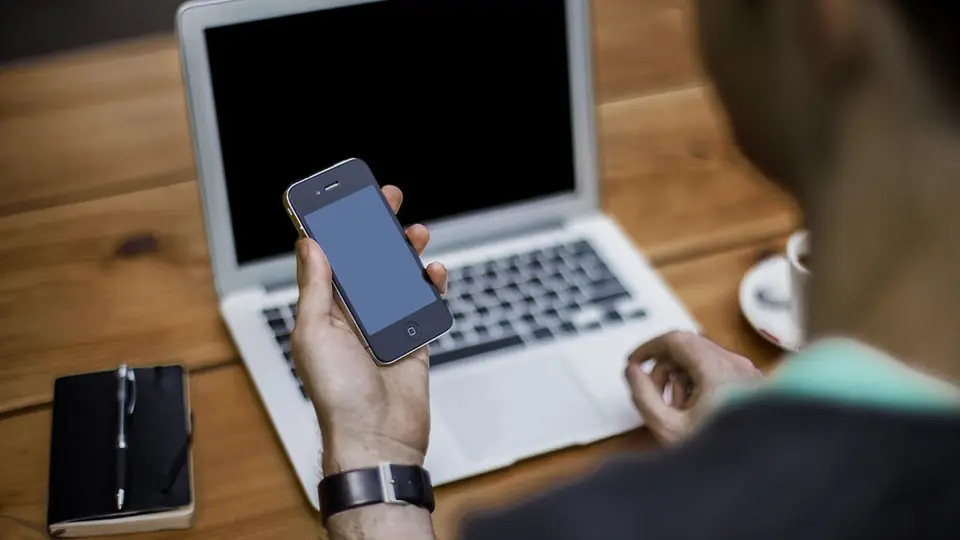 Utiliser un site de rencontre en sécurité : un smartphone en main devant un ordinateur portable