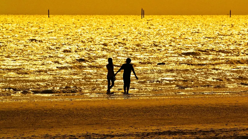 Une nouvelle rencontre après une séparation : deux silhouettes au bord de la mer au soleil couchant