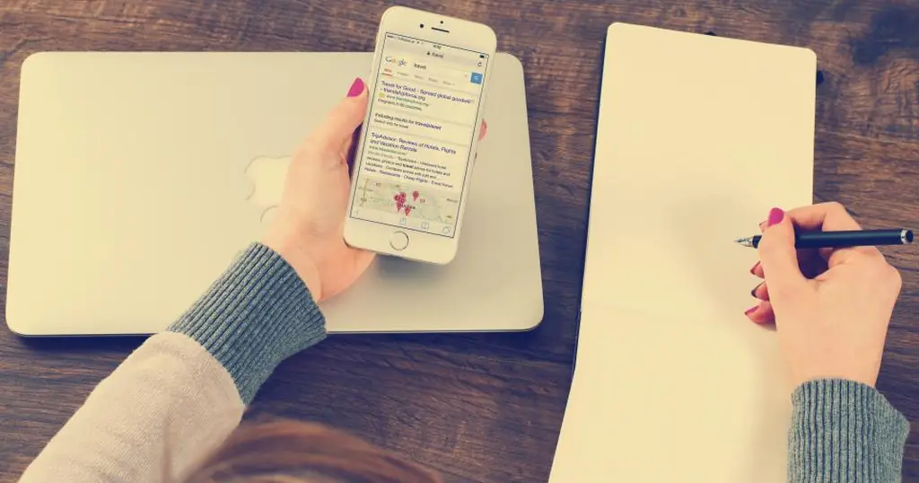 Site de rencontre gratuit : une main tient un smartphone au-dessus d’un carnet