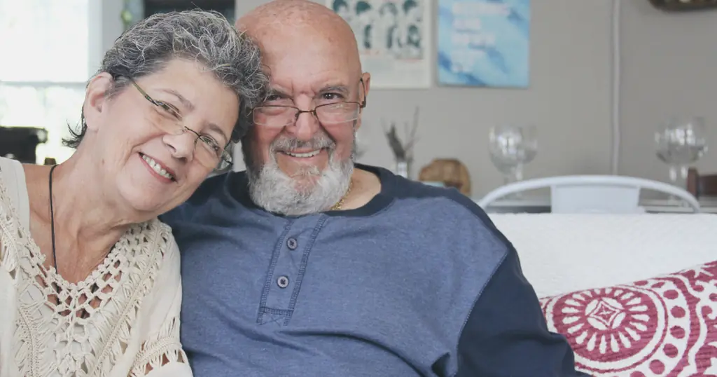 Site de rencontre senior : un couple âgé sourit, assis côte à côte